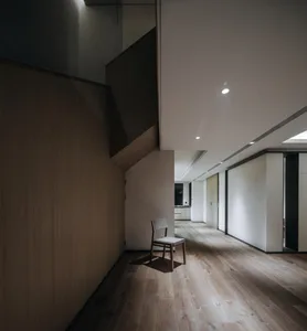 Modern minimalist living room featuring wood flooring and furniture in a clean, uncluttered space.