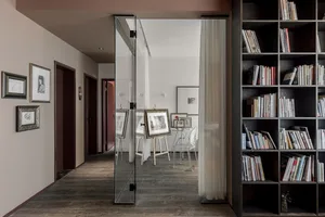 A minimalist home library with dark stone walls, a large bookshelf, and framed artwork.