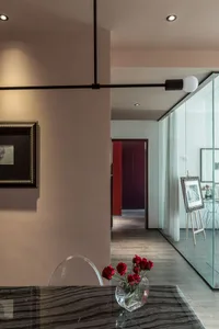 Modern living room featuring a glass dining table with red roses in a vase, sleek lighting, and minimalist decor.