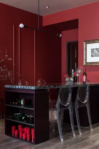 Modern home bar with a marble countertop, wine bottles, and clear plastic chairs.