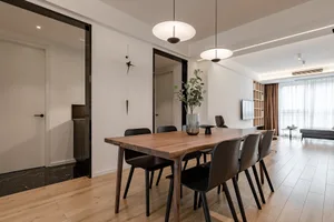 Modern minimalist dining room featuring a wooden table and black chairs, with a minimalist clock on the wall.
