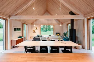 A minimalist living room with wooden furniture and a high ceiling.