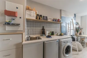 Modern minimalist residential kitchen with white countertops and stainless steel appliances.