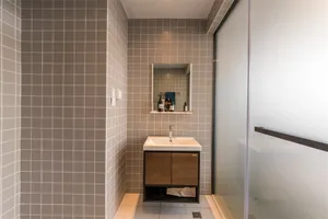 Modern bathroom with gray tile walls, a sink, and a mirror.