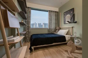 Modern bedroom featuring a wooden bed with a dark cover, a white pillow, and a stuffed animal on the bed. The room has light