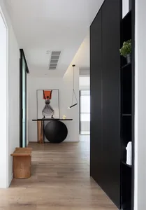 A modern interior design corridor with wooden flooring, a black table, and a black lamp hanging from the ceiling.