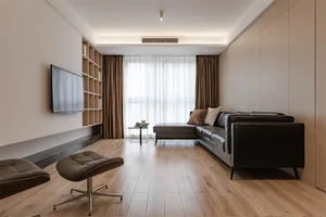 Modern living room featuring a black leather sectional sofa, wooden flooring, and a flat-screen TV mounted on the wall.
