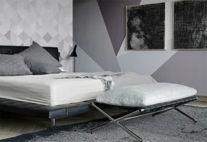A modern minimalist bedroom featuring a black leather bed with grey pillows, a white blanket, and a grey upholstered bench.