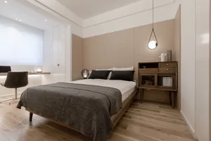 A minimalist bedroom with light wood flooring, a white bed, and black bedding.