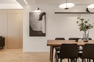 Modern minimalist dining room featuring a wooden table and chairs, with a black and white photograph of a horse on the wall.