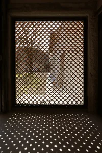 Metal window grid with geometric patterns casting shadows on the floor.