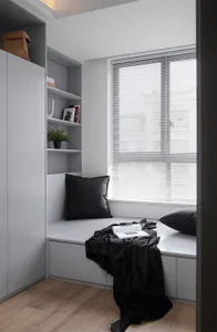 Modern minimalist bedroom with grey blinds and black pillows.
