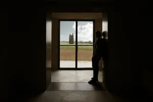 A minimalist window with a glass pane, framed by a dark interior space, overlooking a serene outdoor landscape.