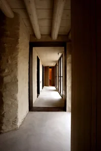 Modern concrete corridor with exposed ceiling beams and wooden panels.