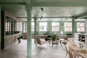 A modern industrial living room with a concrete ceiling, wooden furniture, and glass windows.