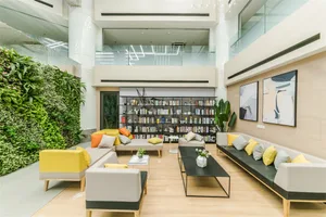 A modern lounge space featuring a variety of materials including upholstered furniture, a green living wall, and a large book