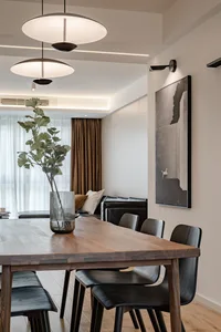 A modern living room featuring wooden furniture, black leather sofa, and a potted plant in a vase.