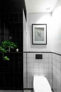 Minimalist black and white bathroom with a white toilet and black tiled walls.