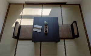 極簡住宅室內，鋪設竹榻榻米地板，搭配木質家具，黑色咖啡桌上擺放陶瓷茶具