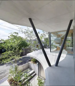 Contemporary concrete balcony with large vertical columns and glass railings overlooking a residential street and surrounding