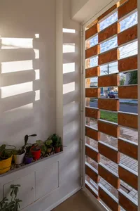 A modern residential interior featuring brick window shutters and a white wall with sunlight casting shadows.