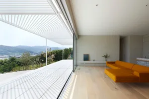 Modern living room featuring a concrete floor and large windows with a view of the mountains.