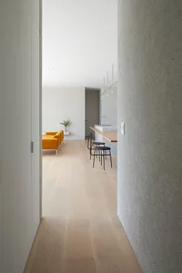 Modern minimalist living room with light wood flooring, a yellow sofa, and a grey textured wall.