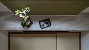 A traditional tea room with wooden shelves, fabric sliding doors, porcelain tea set, and a potted orchid.