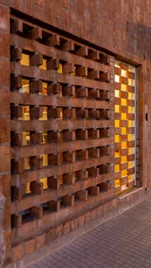 A brick facade featuring a grid pattern with sliced bricks and an illuminated interior.