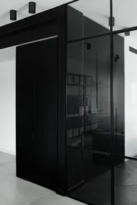 Modern black interior design featuring a glass wall and minimalist furnishings.