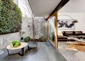 Modern living room featuring exposed concrete walls, a leather sofa, and a minimalist design aesthetic.