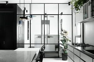 A modern kitchen features a marble countertop and black metal elements.