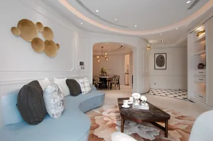Modern living room with curved blue sofa, mixed-media wall art, and marble coffee table.