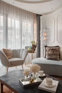 A modern living room with white upholstered furniture, decorative pillows, and a coffee table with decorative items.