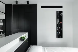 Modern minimalist bedroom featuring black and white color scheme and a bed with white bedding.