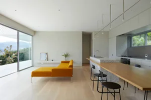 Modern minimalist living room featuring a concrete wall, yellow sofa, and open layout