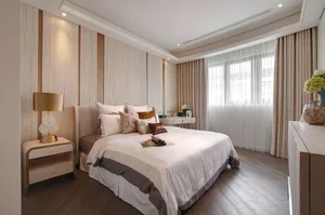 A modern bedroom with a white bed, decorative pillows, and a lamp on a nightstand.