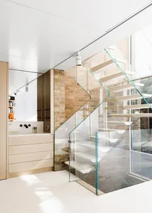 Modern, industrial-style staircase with transparent glass balustrade and white flooring.