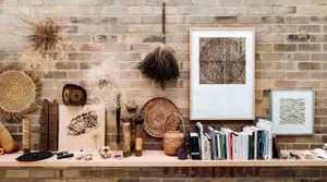 A rustic shelf displaying various organic decor items and books against a brick wall.