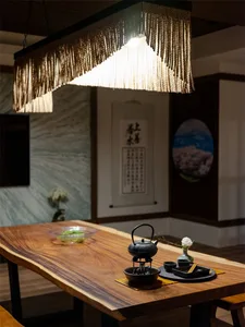 A rustic wooden table with tea ceremony items and a chandelier with fringes