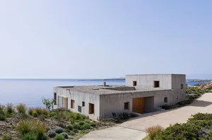 Modern, minimalist house with concrete facade overlooking the ocean.