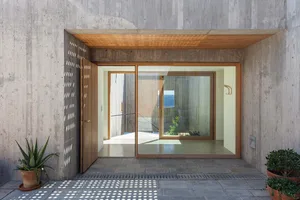 A modern entrance with a concrete wall and large glass window.