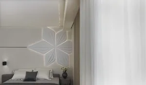 Modern minimalist bedroom with a white star-shaped pattern on the wall, white curtains, and a grey bed.
