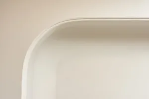 Close-up image of a ceramic bathtub with a curved edge and smooth surface.