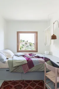 Bedroom with minimalist design, wooden furniture, and colorful fabric blanket