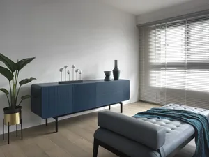 Modern minimalist living room with metallic accents, wooden flooring, and fabric seating.