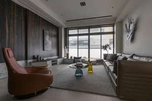 A modern living room with a mix of different materials, including leather furniture, a glass coffee table, and stone accents.