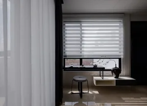 A modern living space featuring minimalist window blinds, a wooden stool, and a vase with a plant.
