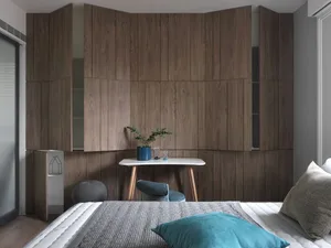 A modern minimalist bedroom with wooden walls and a white desk with a green plant and a blue vase.
