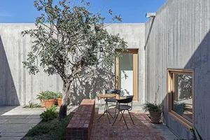 A minimalist patio with a concrete tree and outdoor seating area.